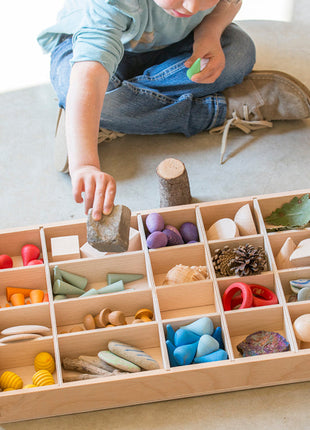 kind speelt met gevulde houten sorteerbak of tinker tray van grapat