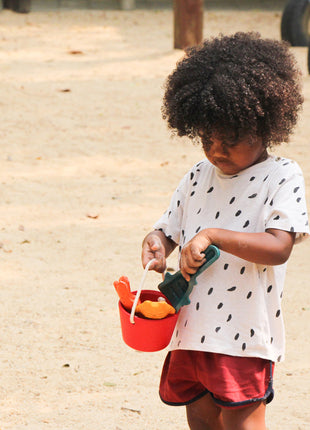 kind speelt op het strand met PlanToys zand speelset emmer en schepjes