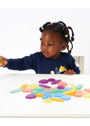 meisje speelt met transparante rainbow pebbles