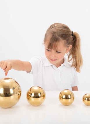 meisje speelt met Tickit 4 sensorische goudkleurige ballen